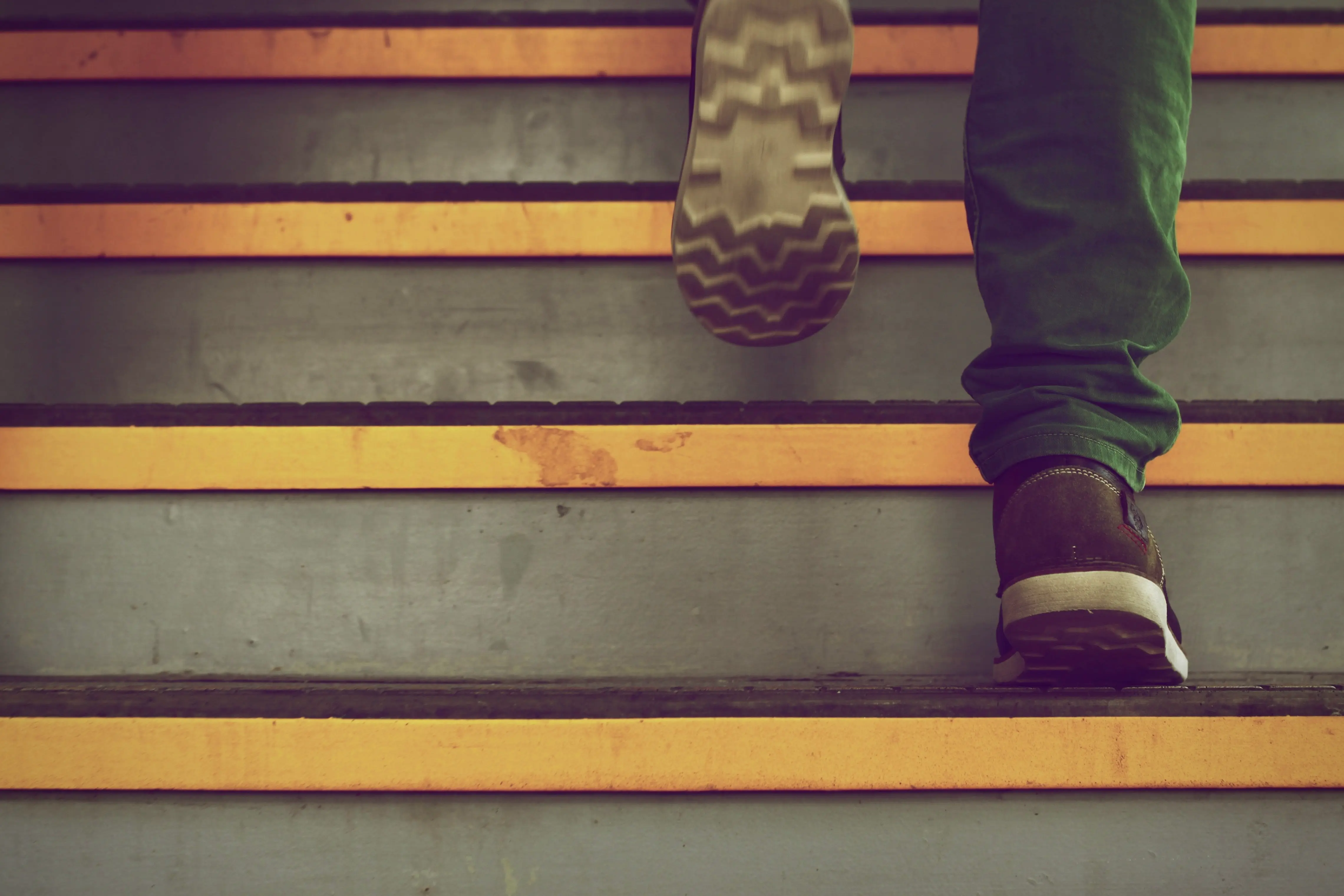Person climbing stairs marked with yellow edge stripes